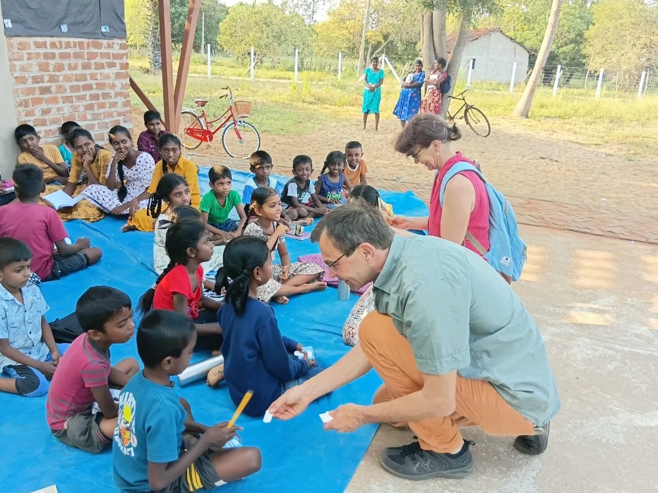 Guests handing out school supplies to children at an outdoor lesson